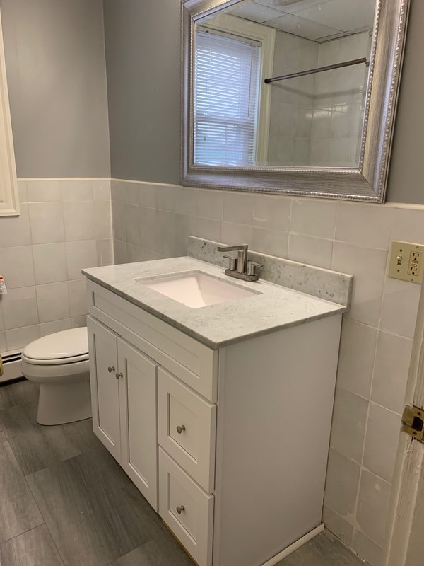 Bathroom with white vanity, marble top and tiled walls at Aruba
