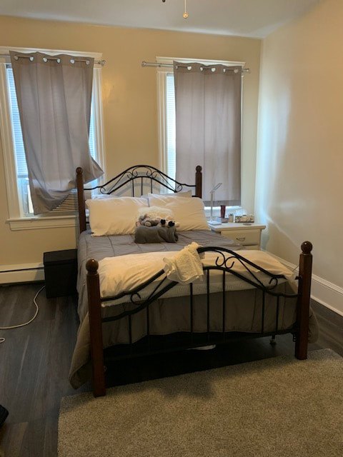 Bedroom with bed frame, nightstand and curtained windows at Aruba