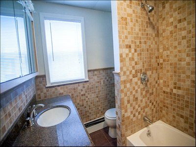 Bathroom with mosaic-tiled tub shower and granite vanity at Cancun