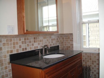 Bathroom vanity with black granite top and mosaic tile wall at Jamaica
