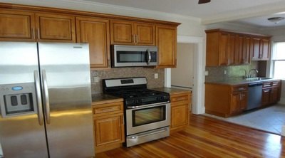 Large kitchen with stainless refrigerator, gas range and wood cabinets at Jamaica