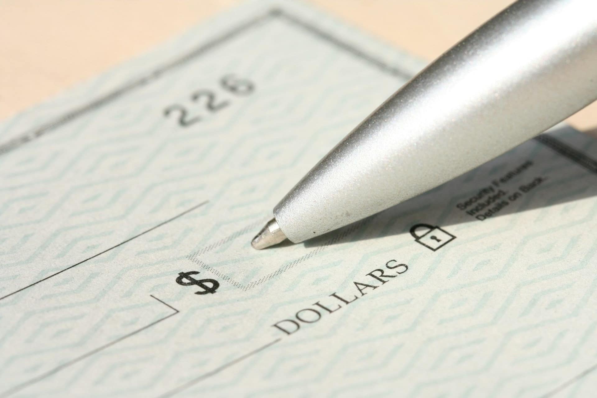 A pen poised over a check, ready to write a rent payment