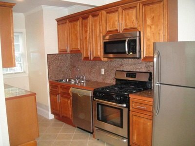 Wood-cabinet kitchen with stainless gas range and mosaic backsplash at South Beach
